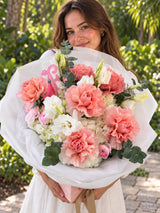 Close-up of Coral Sonnet mixed bouquet with coral roses, white hydrangeas and Fashion Flowers letter topper