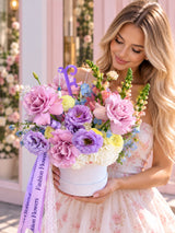 Pastel luxury flower box with purple roses, lavender lisianthus and yellow ranunculus held by a woman - Fashion Flowers Aventura