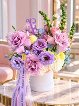 White hatbox flower arrangement with purple roses, lisianthus, ranunculus and Fashion Flowers ribbons - same-day delivery Miami